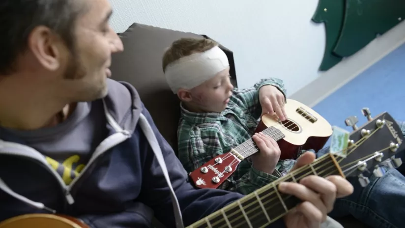 Un homme apprend à un jeune garçon à jouer de la guitare