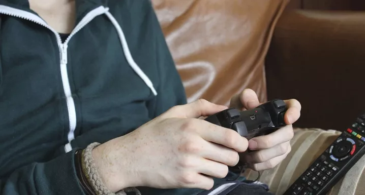 Une personne tient une manette de jeux vidéos dans les mains