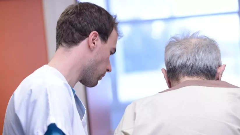 Un soignant accompagne un malade âgé
