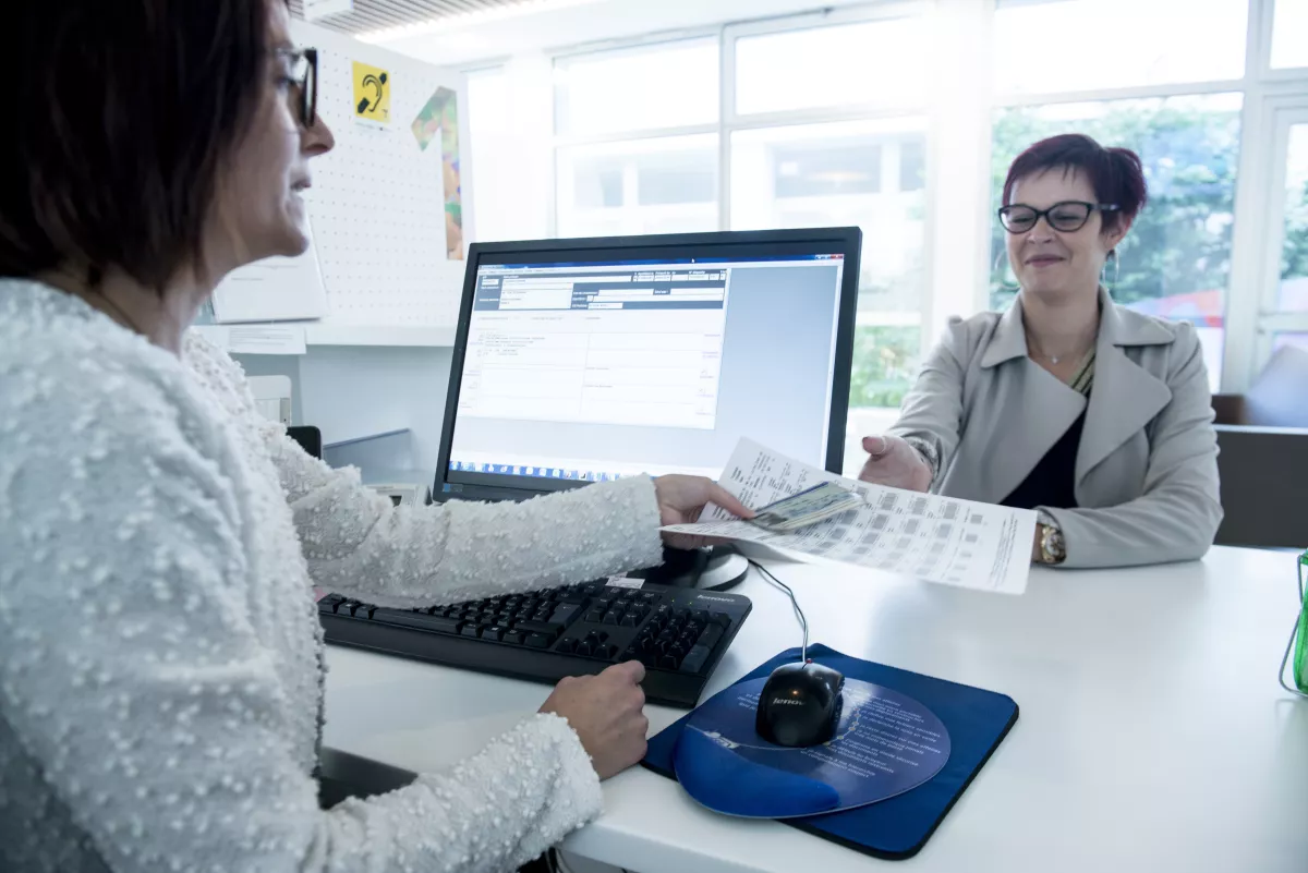 Secrétaire qui donne un document à une patiente