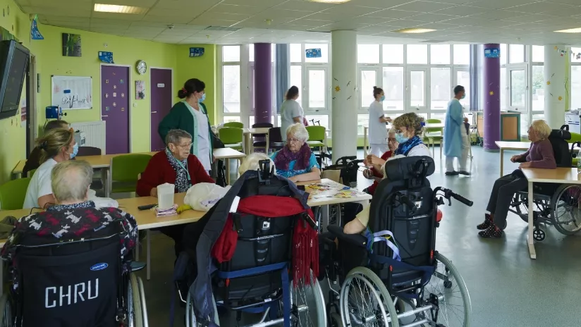 Un groupe de personnes âgées en fauteuils roulants participe à une animation