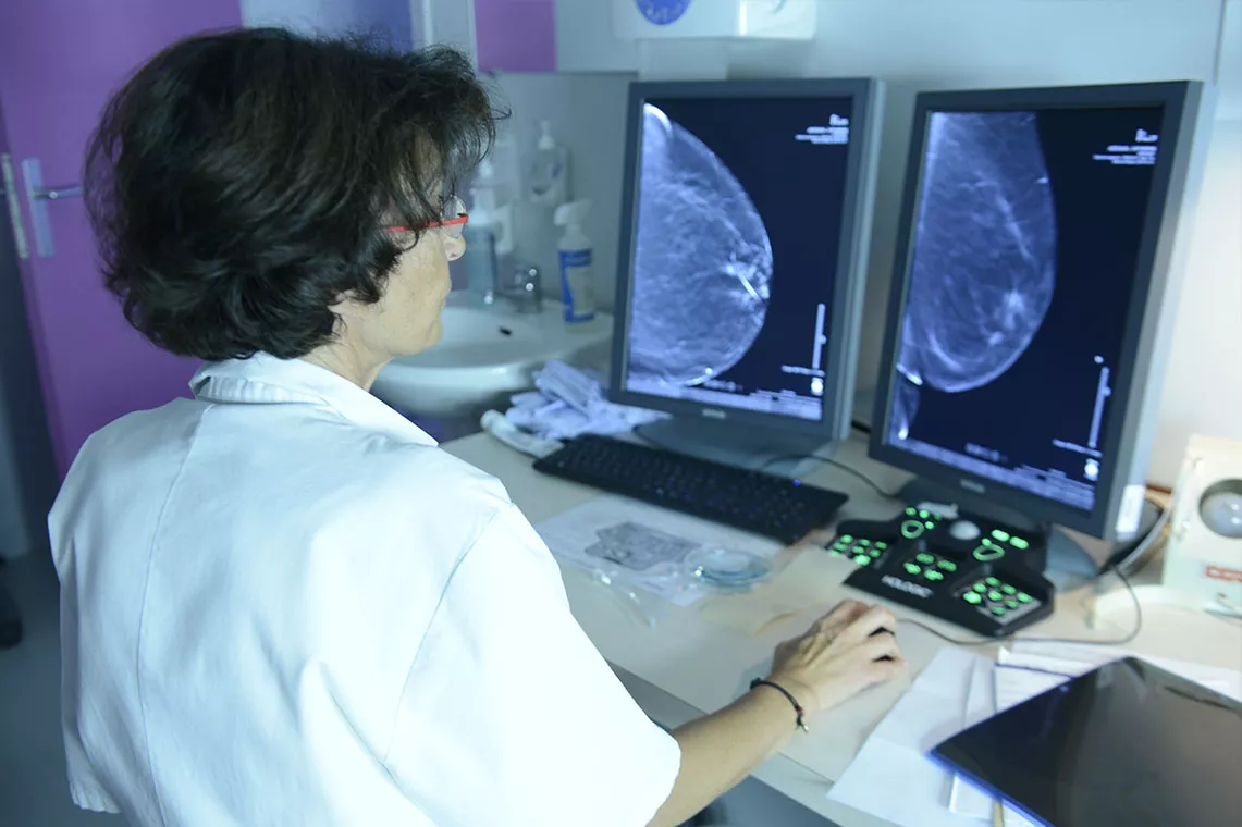 une radiologue regarde sur un ordinateur des images de mammographie
