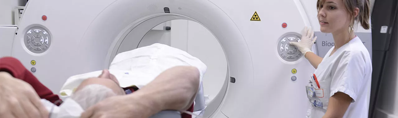 une soignante accompagne un patient dans un appareil IRM
