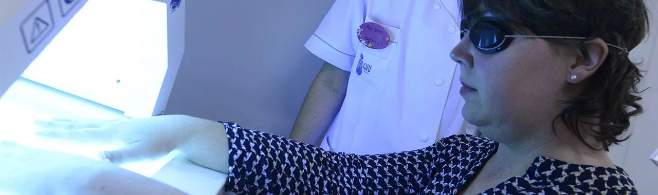 une patiente porte des lunettes spéciales de protection pendant son traitement UV des mains