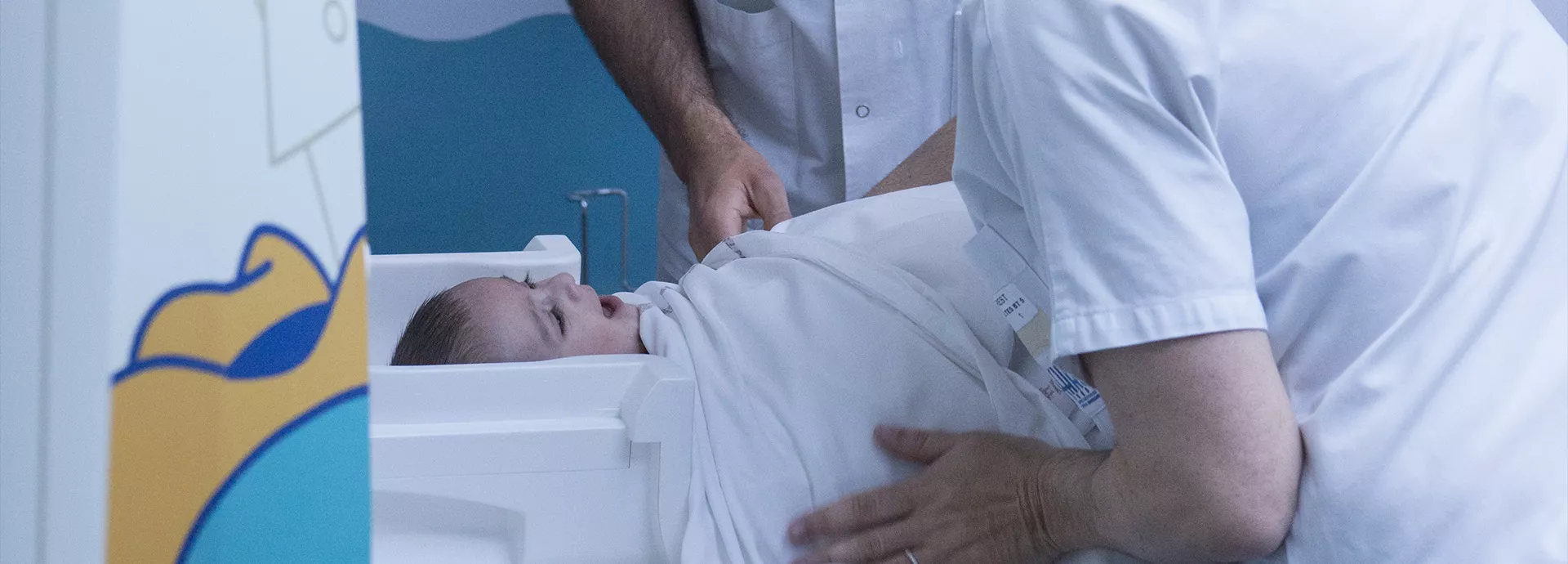 deux soignants parlent à un bébé qui va passer un scanner