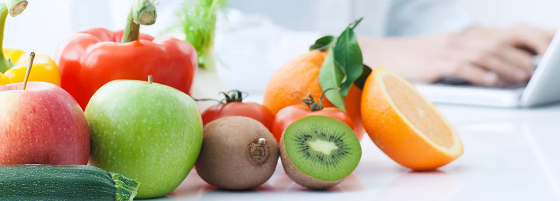 fruits et légumes posés sur une table avec en fond un médecin en blouse blanche devant son ordinateur