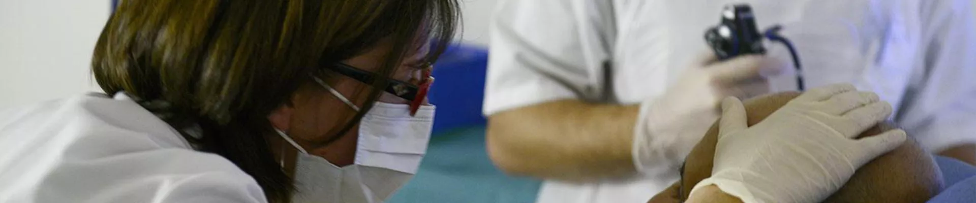 une médecin en blouse blanche et masque pose la main sur un patient pour un soin