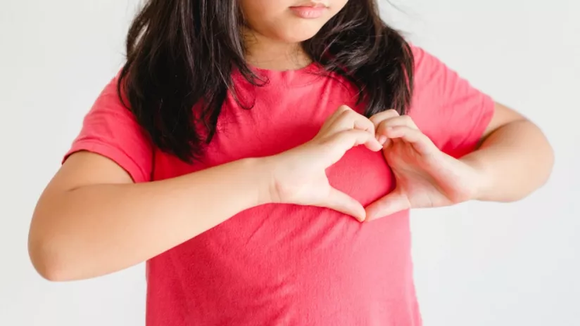 Les mains d'une enfant font un cœur sur sa poitrine pour représenter le don de soi et la gentillesse