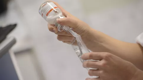 focus sur les mains d'une soignante qui verse un produit dans une poche de perfusion